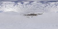 a man is snowboarding on the snowy mountain side and looks down at the camera