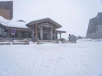 a snowy mountain scene with benches in the snow and a building with glass windows behind it