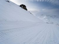 skiers are riding along a snowy mountain side on a trail in the sun,