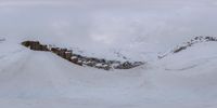 a skiier flying through the air on a snowy hill side and looking down onto some snowy slope