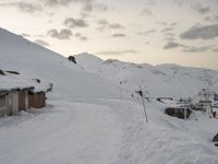 the slopes and houses are covered with snow and are cloudy in the sky over the mountain