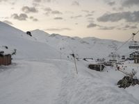 the slopes and houses are covered with snow and are cloudy in the sky over the mountain