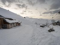 the slopes and houses are covered with snow and are cloudy in the sky over the mountain