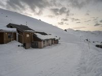 the slopes and houses are covered with snow and are cloudy in the sky over the mountain