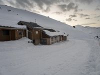 the slopes and houses are covered with snow and are cloudy in the sky over the mountain