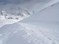 a person on skies standing in front of some mountains in the snow under a cloudy sky