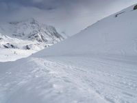 a person on skies standing in front of some mountains in the snow under a cloudy sky