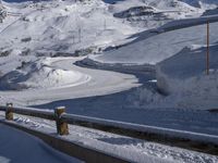 there is snow on the side of a mountain road as a skier is going down it