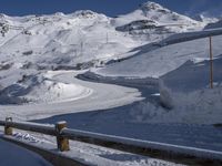 there is snow on the side of a mountain road as a skier is going down it