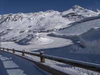 there is snow on the side of a mountain road as a skier is going down it