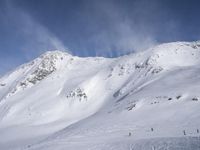 people skiing down a steep mountain slope with clouds in the sky and snow covering the ground