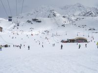 some skiers are at the bottom of a snowy mountain near an approaching lift and a resort