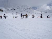 some skiers are at the bottom of a snowy mountain near an approaching lift and a resort