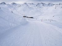 snow covered slope in the middle of a ski area as people ski on it near ski lift