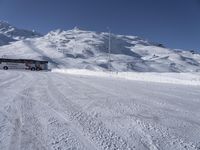 a large bus driving through the snow covered ground in front of some mountains, and the view of the ski lift to the top