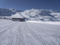 a large bus driving through the snow covered ground in front of some mountains, and the view of the ski lift to the top