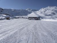 a large bus driving through the snow covered ground in front of some mountains, and the view of the ski lift to the top