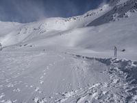 a mountain with people on skis and snowboards in the foreground, one on a cross country trail in front of the other