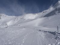 a mountain with people on skis and snowboards in the foreground, one on a cross country trail in front of the other