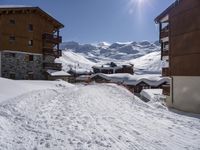 a person walking on a ski path in the snow next to buildings in a mountain town