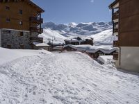 a person walking on a ski path in the snow next to buildings in a mountain town