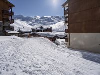 a person walking on a ski path in the snow next to buildings in a mountain town