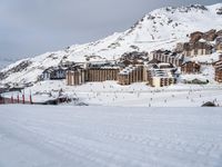 people skiing on a snowy area next to ski lodge in ski resort town in mountainside