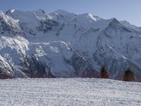 people riding skis down a snow covered slope next to tall mountains and snow capped peaks