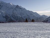 people riding skis down a snow covered slope next to tall mountains and snow capped peaks