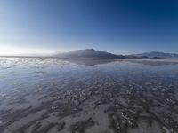 a body of water that is frozen in some land by the mountain range next to it