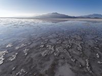 a body of water that is frozen in some land by the mountain range next to it