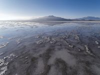 a body of water that is frozen in some land by the mountain range next to it