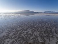 a body of water that is frozen in some land by the mountain range next to it