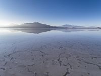 a body of water that is frozen in some land by the mountain range next to it