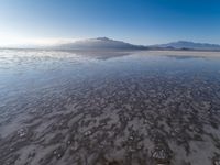 a body of water that is frozen in some land by the mountain range next to it