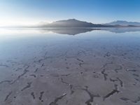 a body of water that is frozen in some land by the mountain range next to it