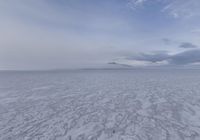 a view of a frozen lake with ice on the water and mountains in the distance