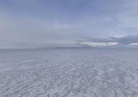 a view of a frozen lake with ice on the water and mountains in the distance