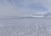 a view of a frozen lake with ice on the water and mountains in the distance