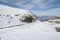 the person is standing on a mountain side road in the snow and skies over head