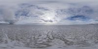 a panoramic photograph of a view over an open, frozen plain with a few snow