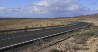 a scenic road runs through a desert and some mountains at the side of it in an open area