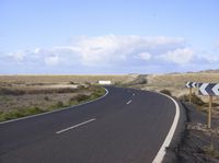 an empty road with an arrow sign pointing left and right and to the right, on the side of the road
