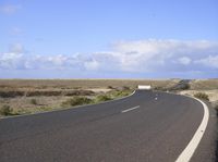 an empty road with an arrow sign pointing left and right and to the right, on the side of the road