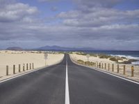 a highway that is open to the water and beach shore with an empty road next to it