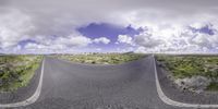 a long curved road with a sky background on the side, with grass growing between it