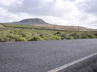 a lone skateboard is shown on a country road near a hilly area with hills