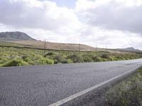 a lone skateboard is shown on a country road near a hilly area with hills