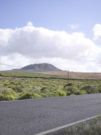 a lone skateboard is shown on a country road near a hilly area with hills