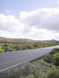 a lone skateboard is shown on a country road near a hilly area with hills